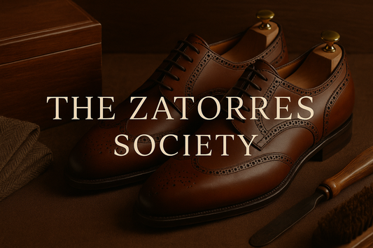Brown leather wingtip Oxford shoes with The Zatorres Society text overlay, displayed on a rich brown background with shoe care tools.